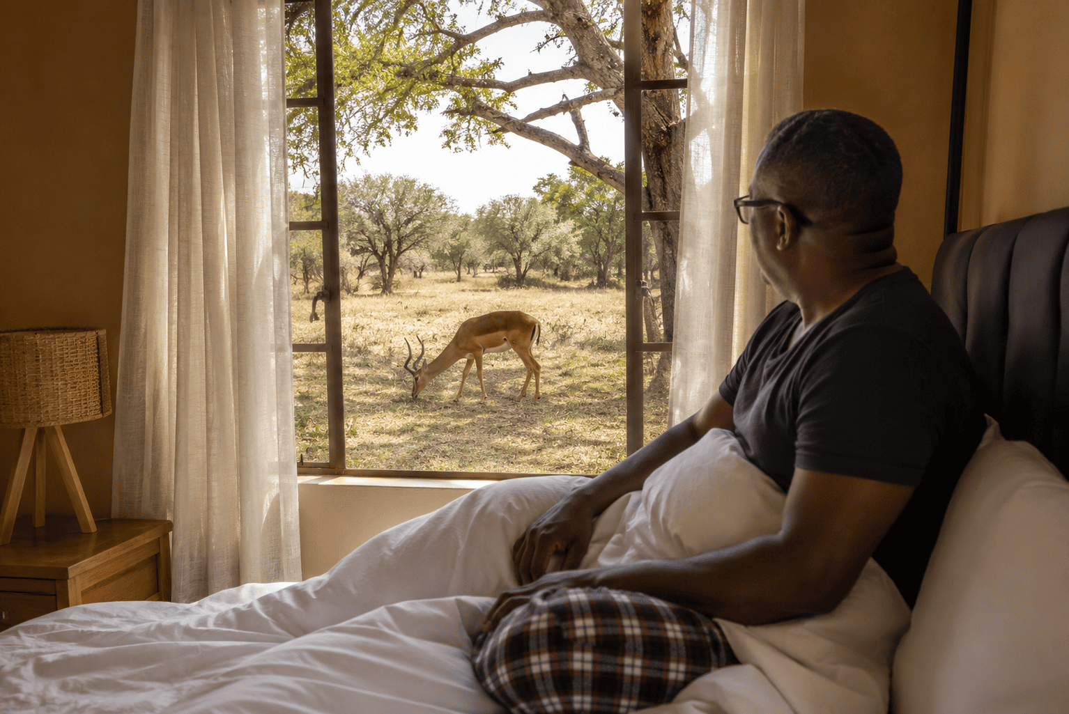 Guest watching an impala from a Ku-Wa Safari Lodge room